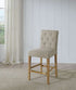 Port Royal Counter Height Stool with white oak finish, beige linen upholstery, tufted backrest, and wooden legs with footrest.
