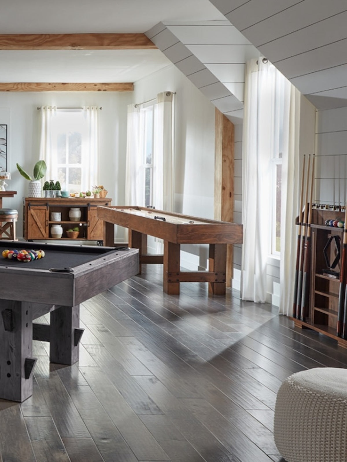 The American Heritage Bristol billiard table in a game room with a shuffleboard and pool cue rack.